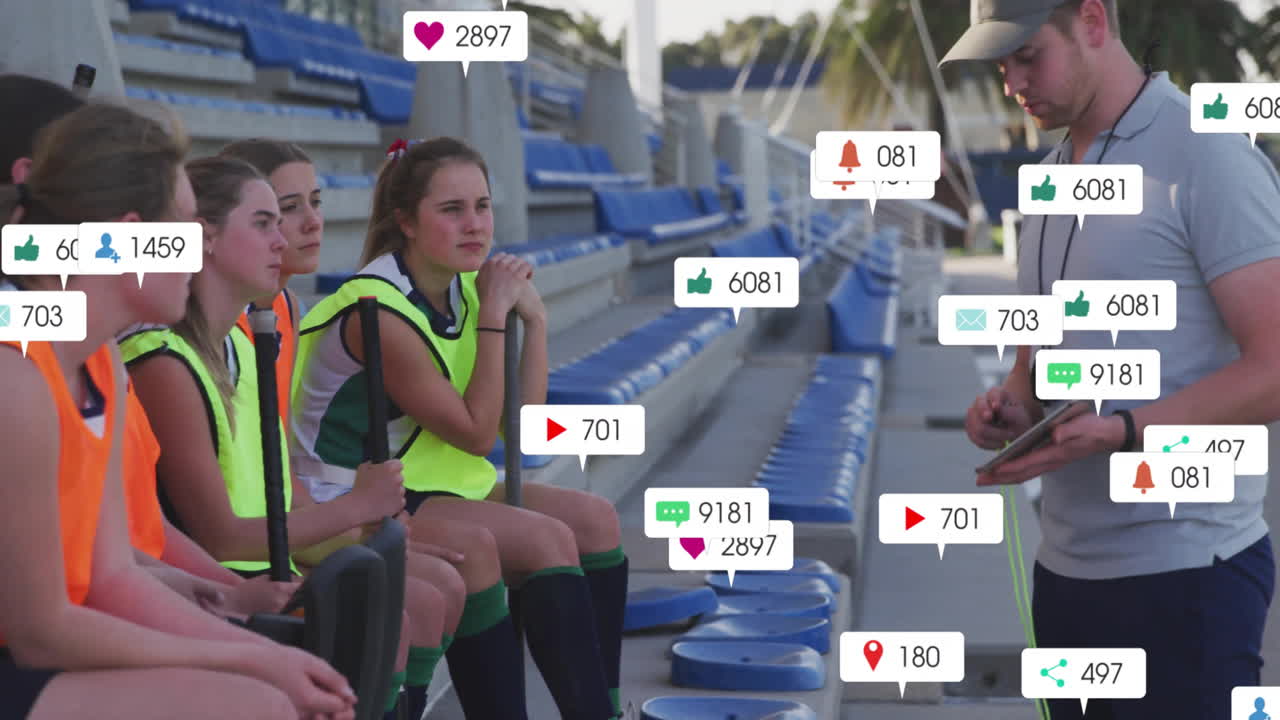 Sports marketing team sitting on bleachers, coach using tablet with floating social icons
