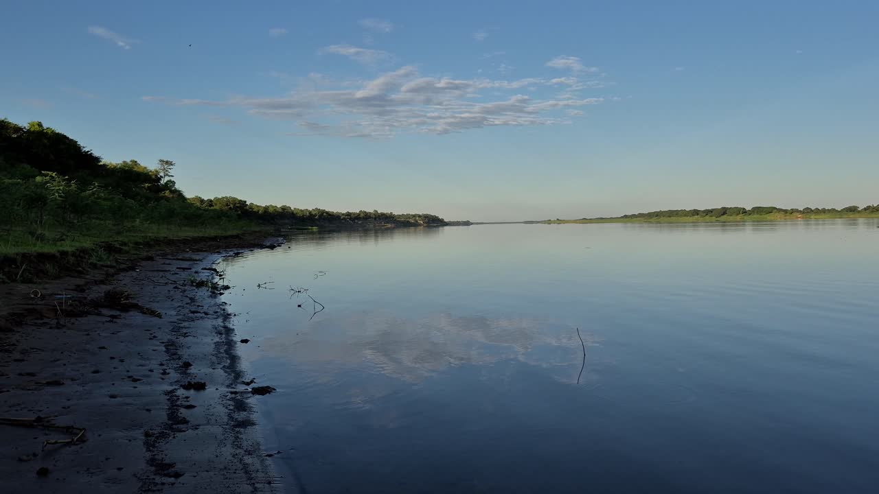 A peaceful morning by the river, showcasing calm waters with clouds beautifully reflected and fish feeding. Captured in stunning 4K at 60fps, perfect for nature and serenity themes.