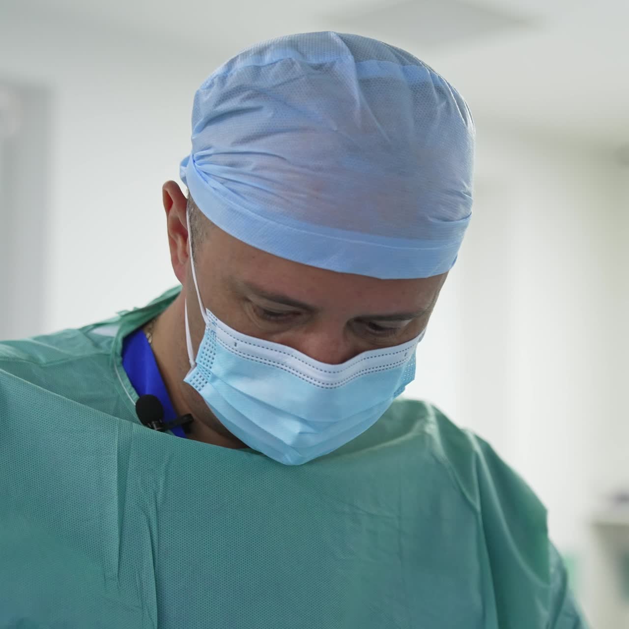 Portrait of surgeon in mask during operation. Male doctor in medical uniform performs a plastic surgery in the operating room