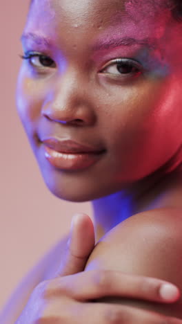 vertical video of african american woman with short dark hair in blue and pink light, slow motion