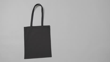 Close-up-of-black-bag-on-grey-background,-with-copy-space,-slow-motion