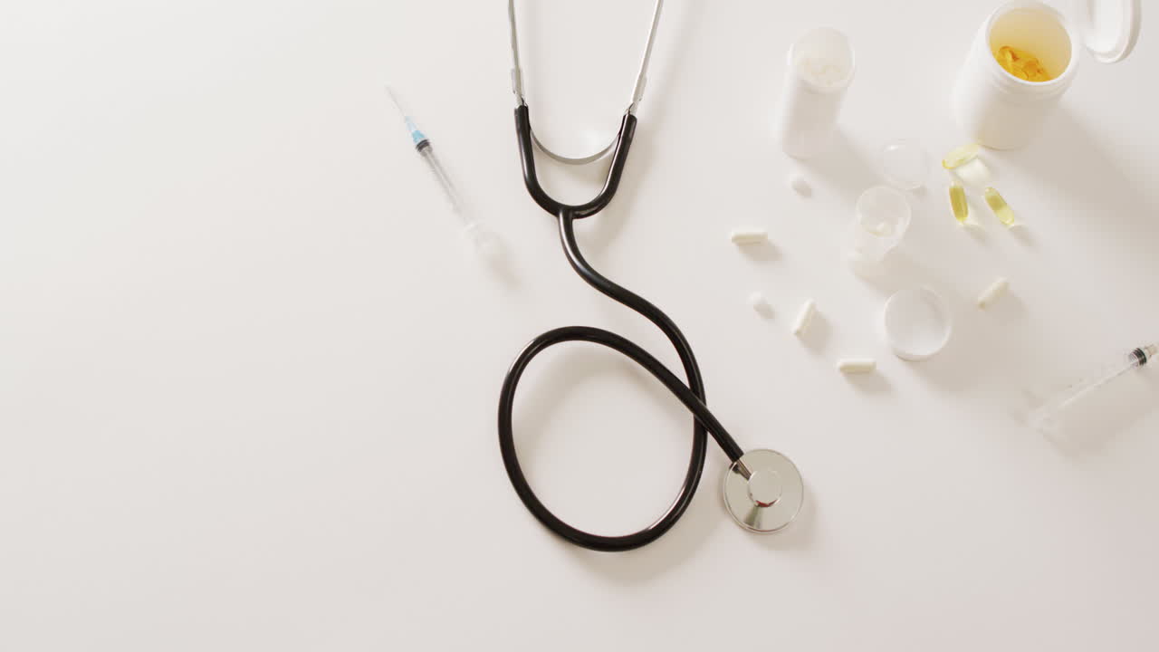 vídeo del estetoscopio, la jeringa, las pastillas y las cápsulas sobre fondo blanco con espacio para copiar