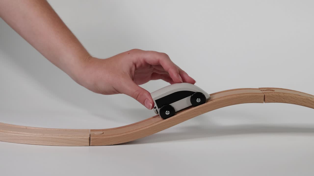손은 물결 모양의 트랙에서 장난감 차를 움직인다