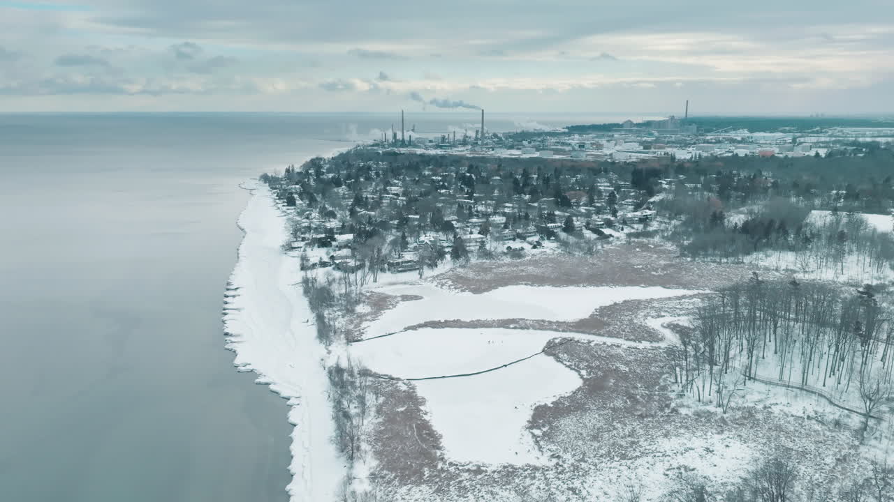 雪景空拍圖，冰封濕地鄰近工業城市景觀。