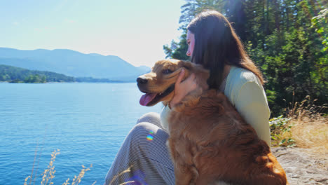 Young-Lady-Sitting-Outdoor-Waterfront-Petting-Her-Golden-Retriever-Dog,-Cinematic-Orbital-View