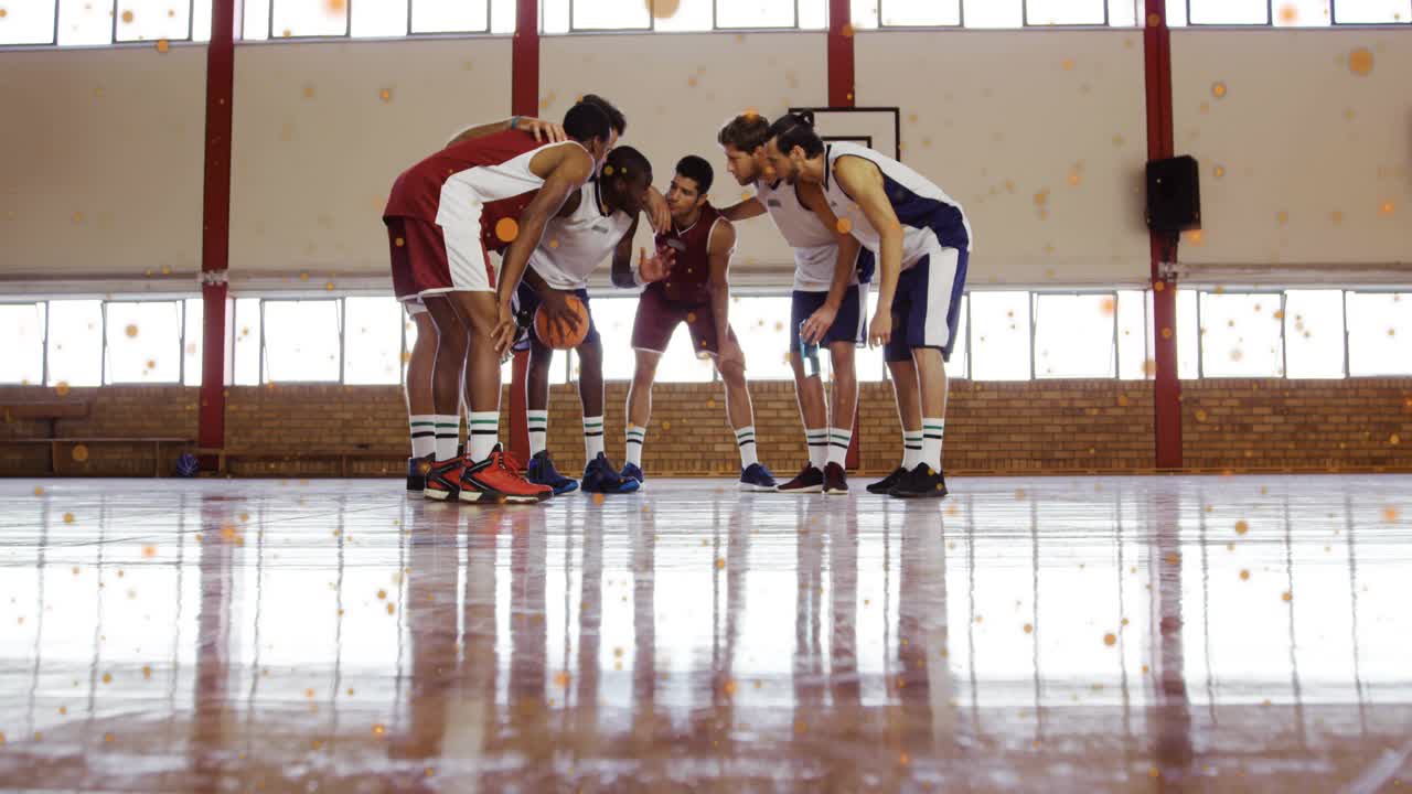 Basketball team forming midcourt huddle, holding phone and activating orange particles for strategy