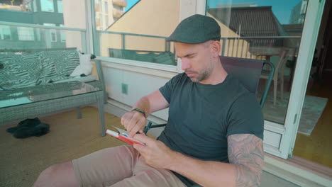 man making notes on paper notepad while relaxing and drinking coffee - close up