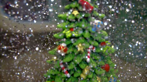 silver snow particles floating around christmas tree in snow globe