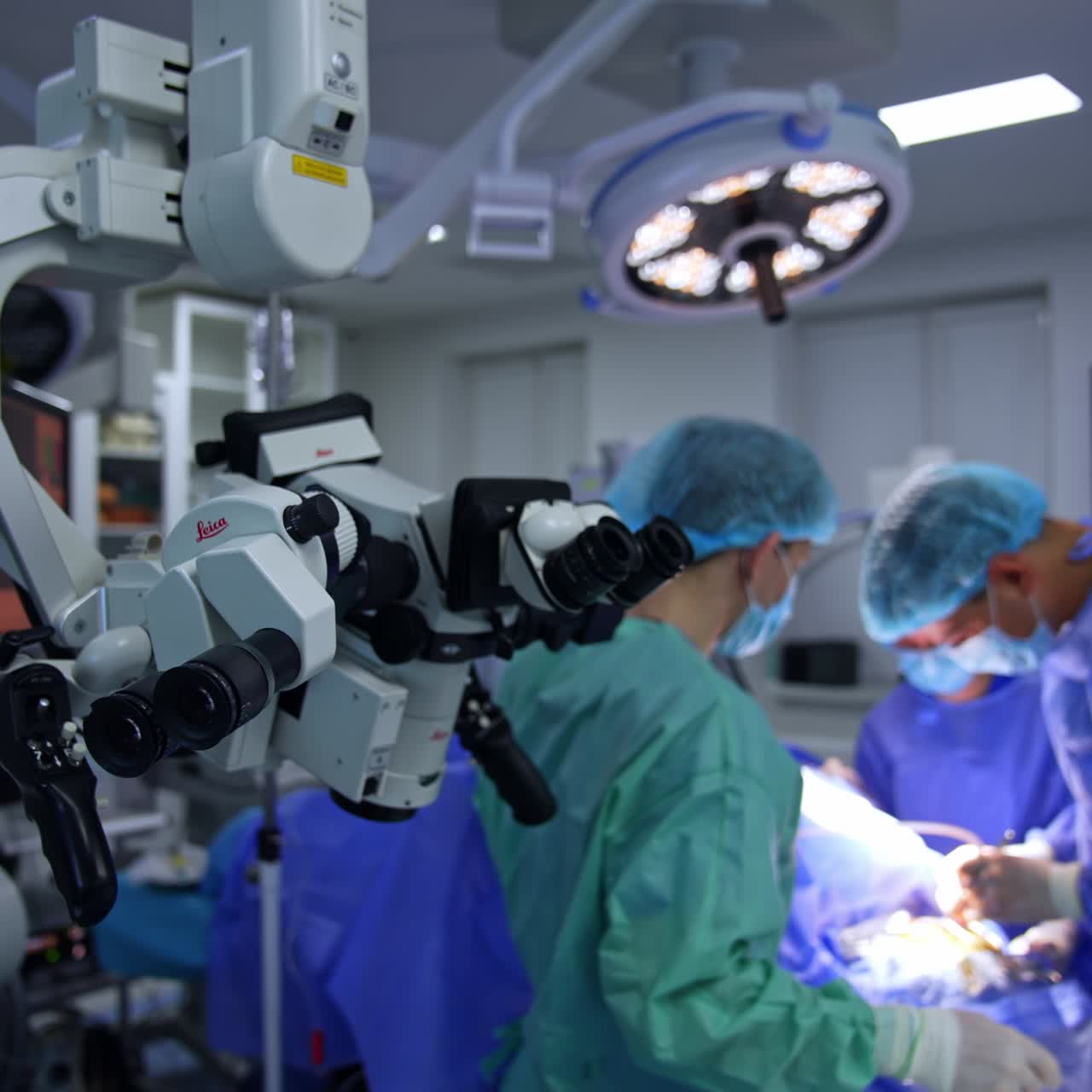 Hi-tech surgical microscope with two pairs of binoculars in operational room. Medics conducting surgery at backdrop in blur