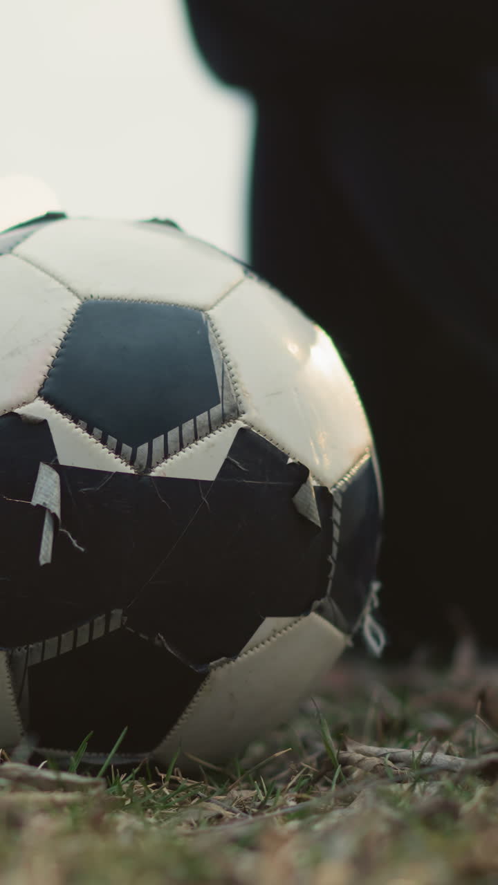 Close-up of a soccer ball on a grassy field with a blurred view of two people seated behind