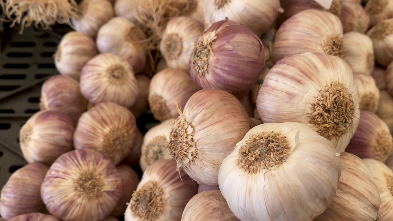 Grandi bulbi d'aglio fresco esposti in un mercato locale a Cascais, Portogallo, che mostrano prodotti naturali, texture vivaci e l'autentica cultura culinaria portoghese