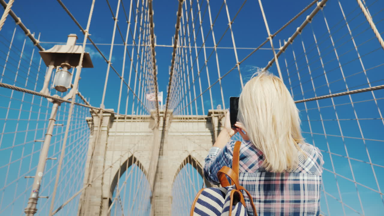 한 여성이 유명한 브루클린 다리에서 자신의 사진을 찍습니다.