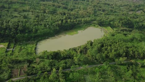 Aerial-flight-over-lake-result-of-volcanic-sand-mining-surrounded-by-green-jungle-of-Indonesia-during-sunny-day-misty-day