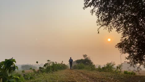 Wide-view-of-athletic-young-man-jogging-towards-camera-on-winter-morning,-rural