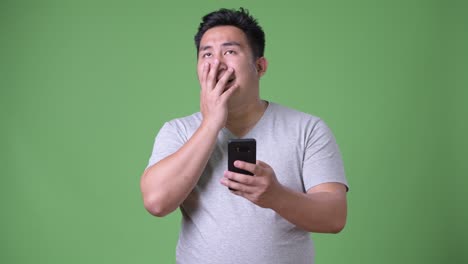 young handsome overweight asian man against green background