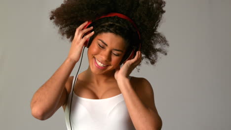 chica bonita con afro saltando y escuchando música