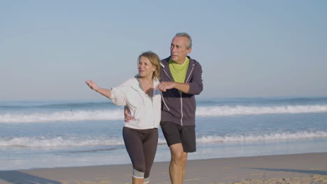 Un-Anciano-Alegre-Y-Una-Mujer-Abrazándose-Y-Caminando-Por-El-Océano