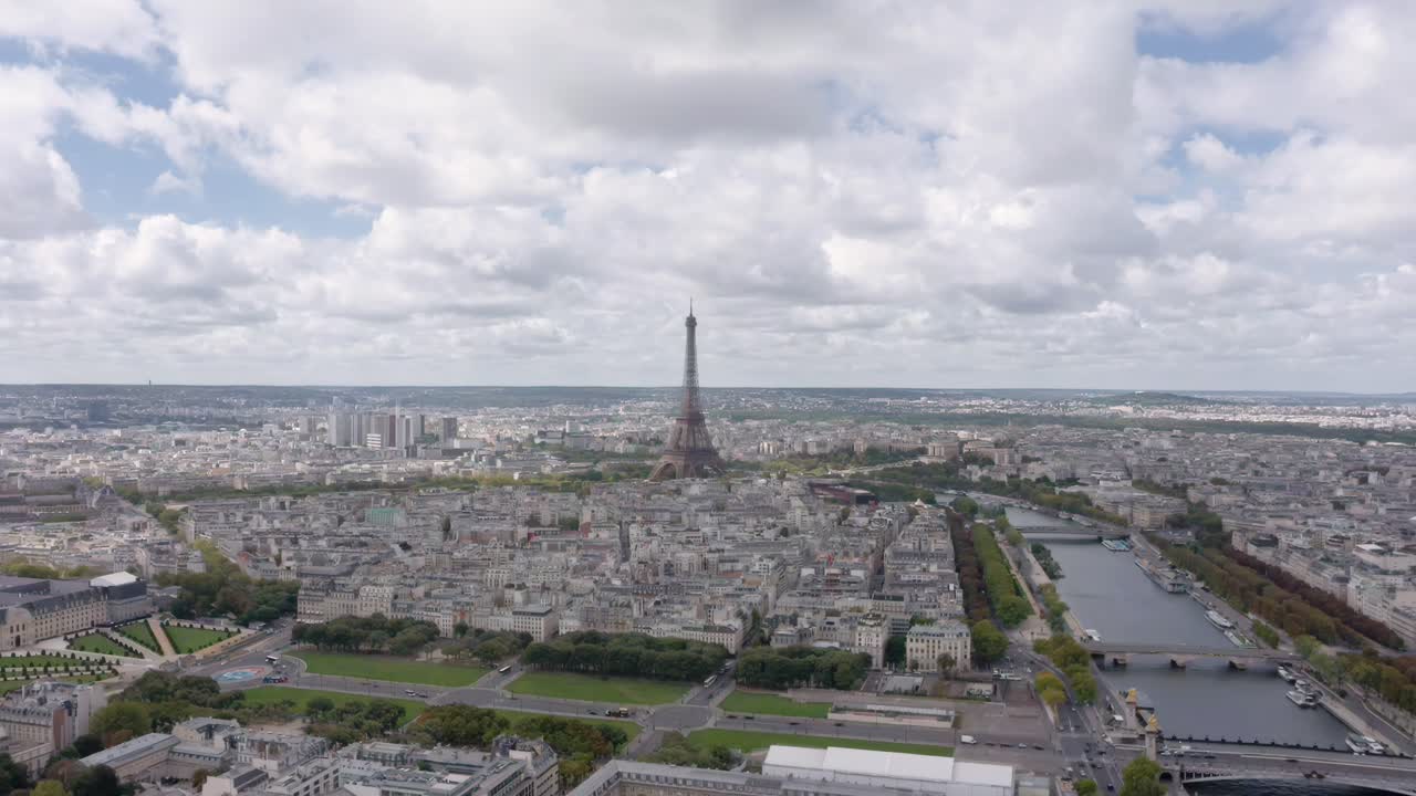 A breathtaking aerial drone shot flying backwards from the Eiffel Tower above Paris with the Seine River winding through the city’s historic skyline