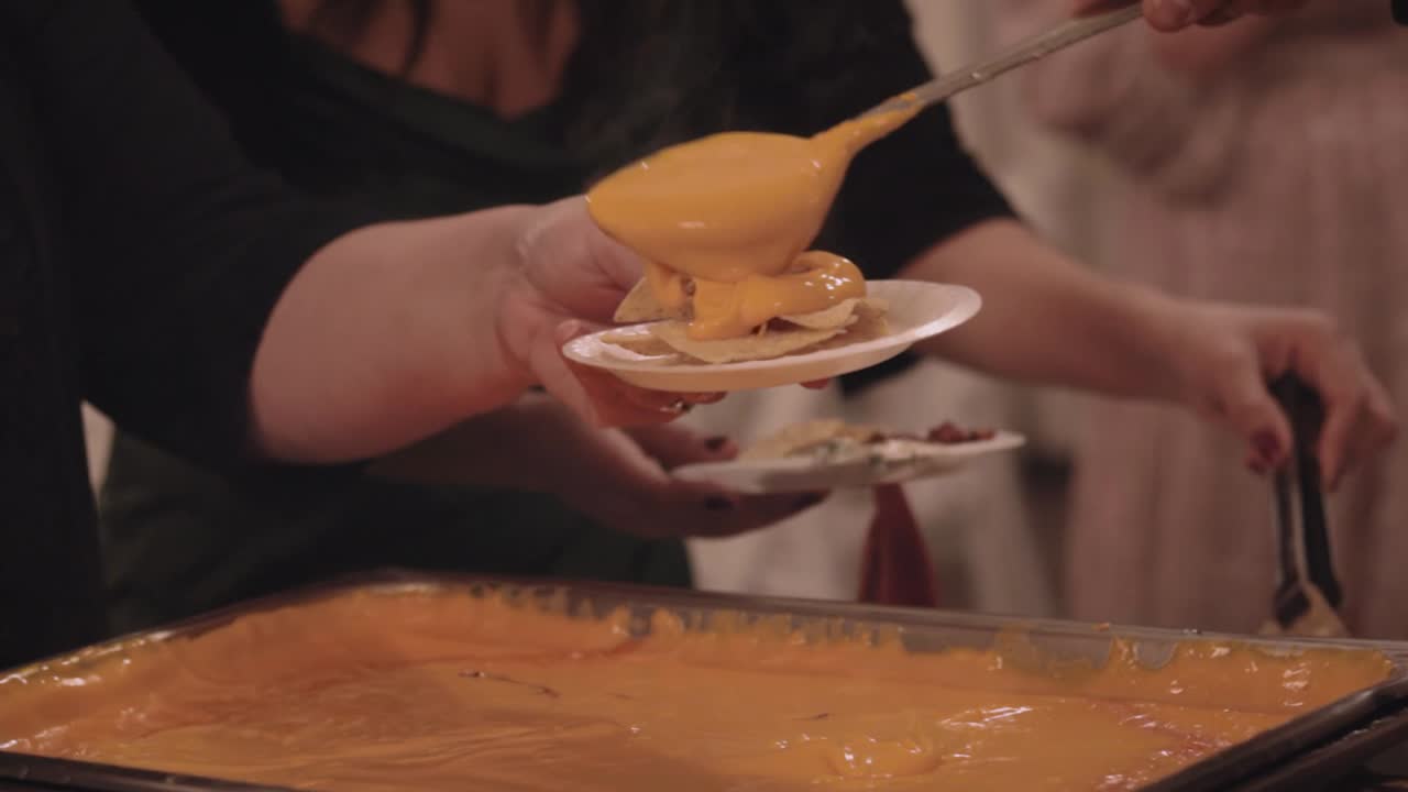 Gooey Hot Steamy Cheese Being Scooped Onto Plate Of Nacho Chips At Buffet