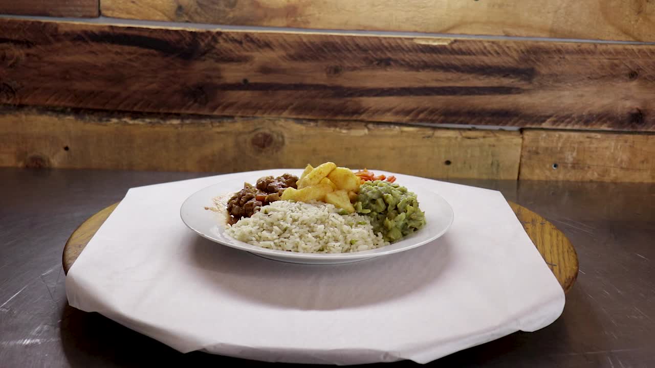 Ampia ripresa di un piatto girevole (lazy susan) con stufato di manzo, riso, patate fritte, carote e purè di fagioli