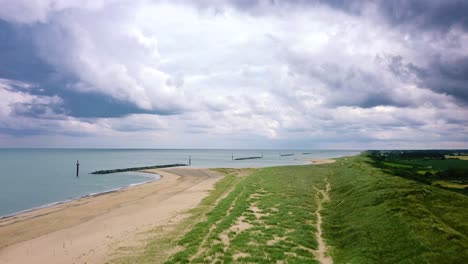 A-storm-brews-with-grey-moody-clouds-over-a-beautiful-beach-seascape,-Britain