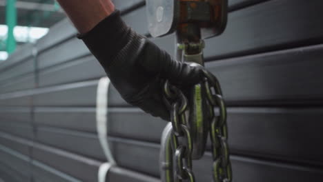 industrial manufacturing worker attaching steel chain to lifting hook