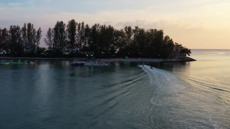 Sunset-aerial-view-capturing-banana-boat-ride-back-to-the-shore-at-paradise-101,-fun-inflatable-water-activity-at-Langkawi,-Kedah,-Malaysia,-Southeast-Asia