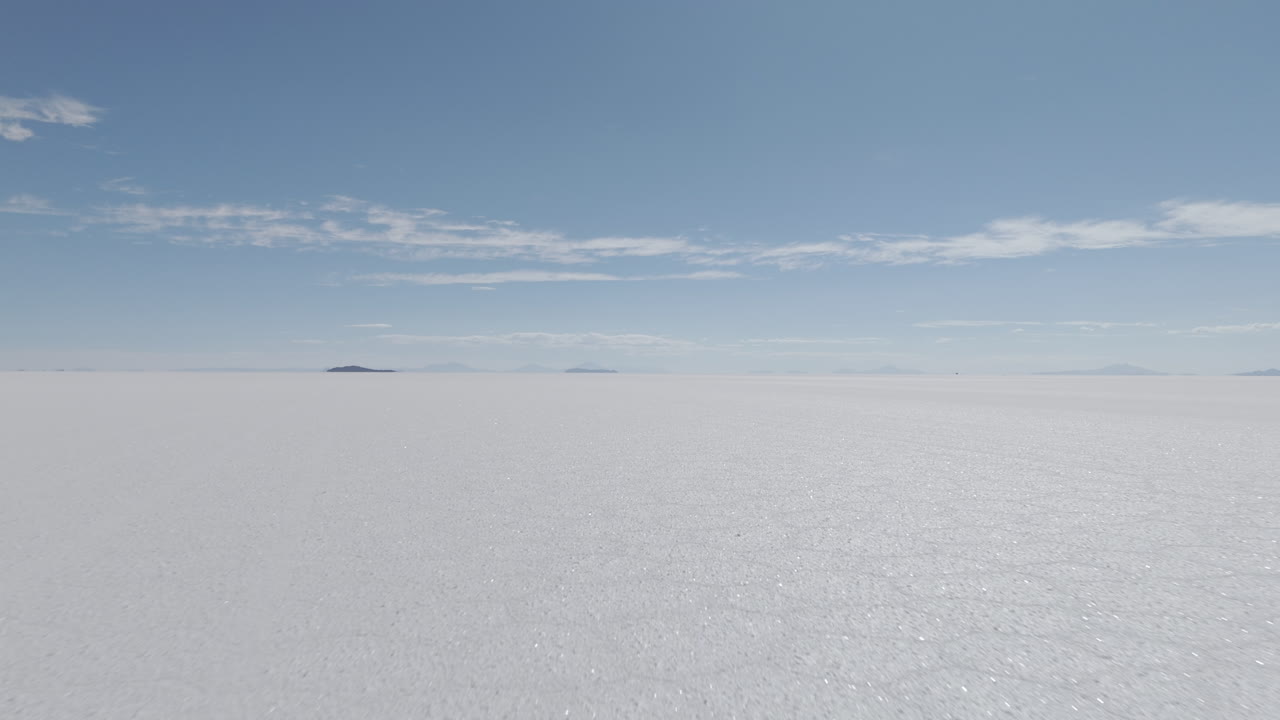 Drone shot flying above the dry salt flats in Bolivia Uyuni on the cloudy day with some small hills in the background LOG