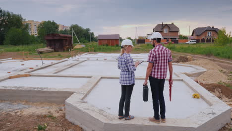 dos constructores: un hombre y una mujer están en la base del futuro edificio discutiendo el plan de trabajo