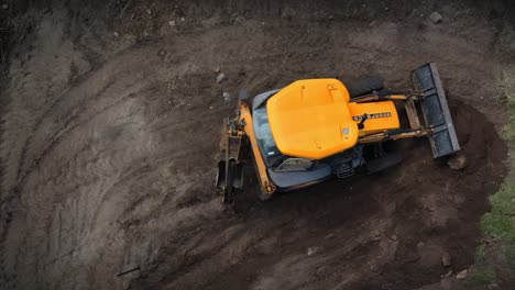 yellow digger moves soil around on a plot of land, clearing to build