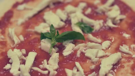 Italian-Chef-Putting-Fresh-Basil-leave-on-Almost-ready-Margherita-Pizza