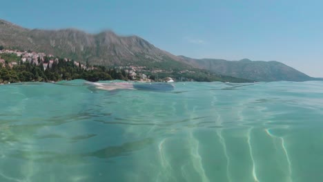 Split shot, half underwater half mountain landscape, Young boy swims in Crystal clear waters