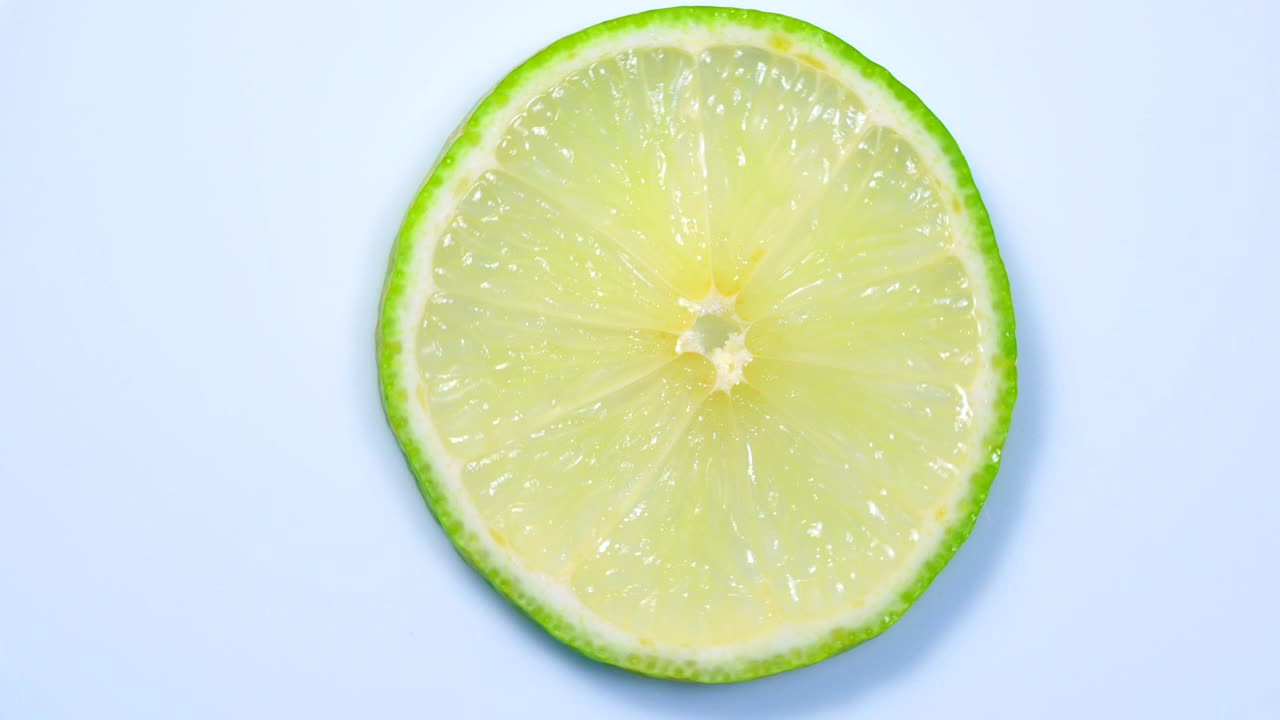 una rebanada de limón verde está girando lentamente en el estudio con los detalles.