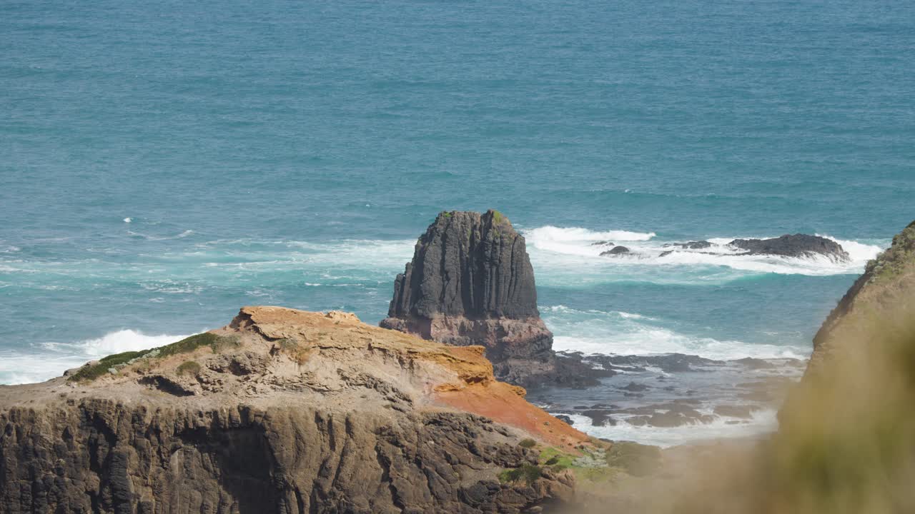 Daylight pan reveals rugged cliffs, ocean waves, and iconic rock formation at Cape Schanck