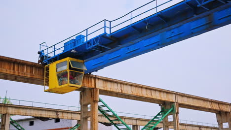 yellow booth with a working person inside. construction crane machinery at the backdrop of grey sky.