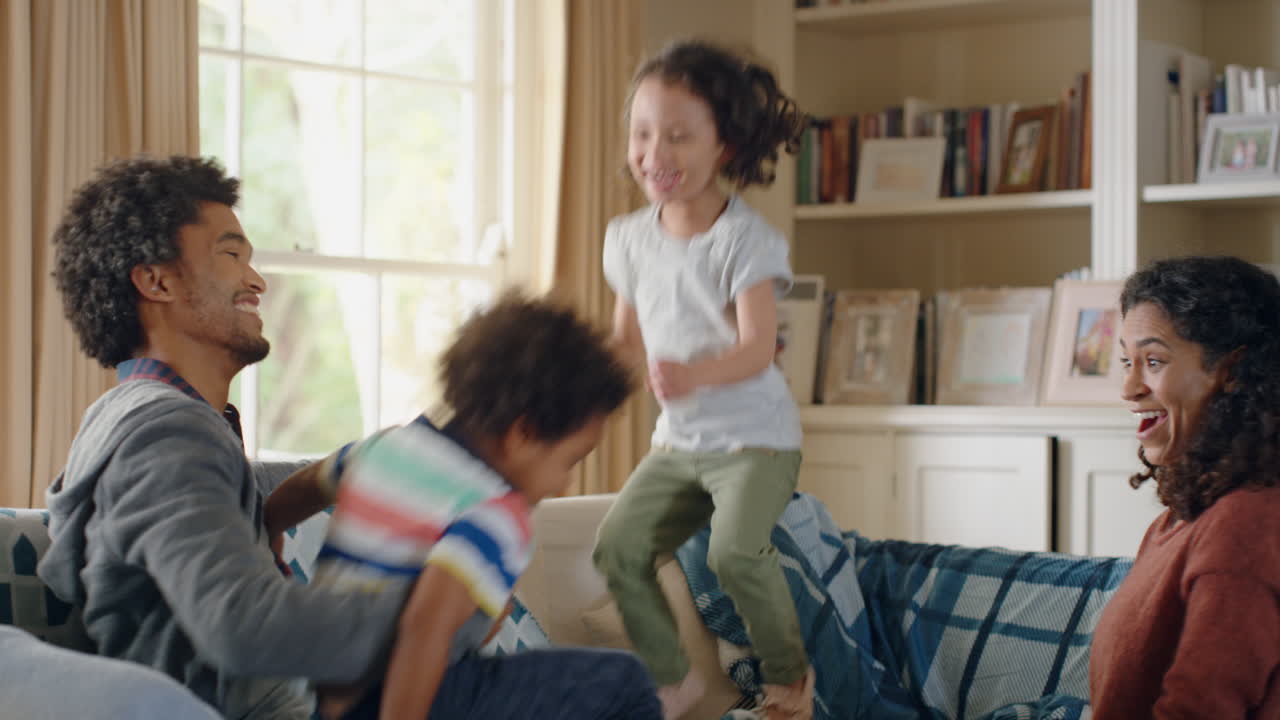 happy children jumping on sofa enjoying playing game at home having fun together on weekend with parents