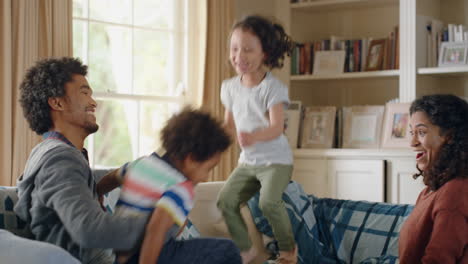 happy children jumping on sofa enjoying playing game at home having fun together on weekend with parents