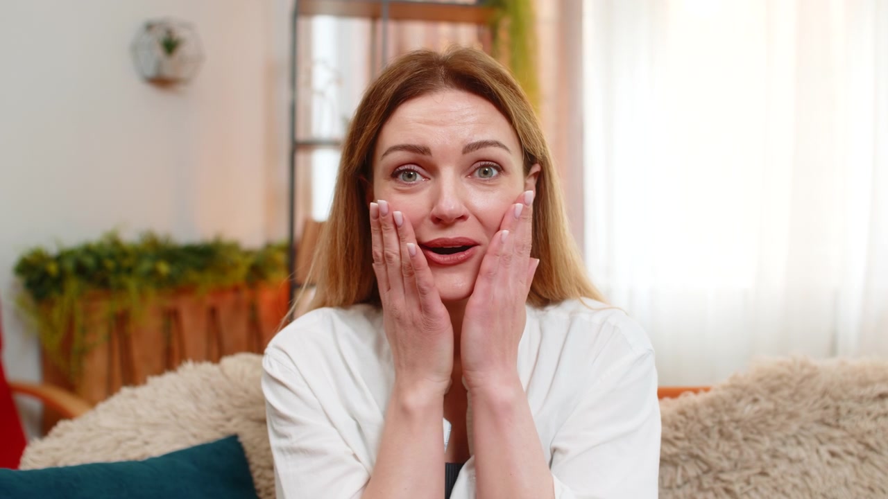 Adult woman looking at camera with surprise at home wide eyes and wow expression showing excitement