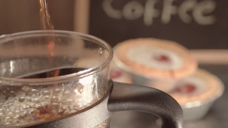 pouring fresh coffee into a pot with cherry cake