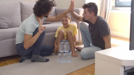 Two-focused-dads-and-boy-sitting-on-floor-at-home