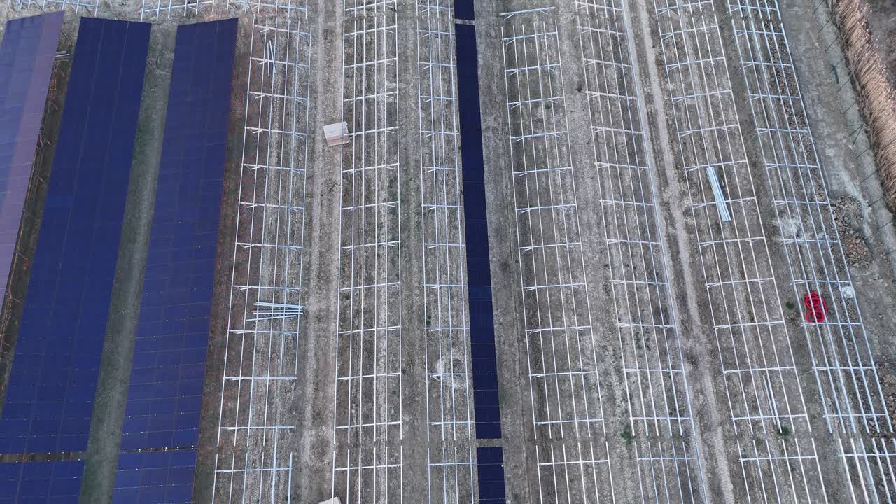Solar array construction with photovoltaic panels and metal support structures covering agricultural fields, implementing renewable energy and sustainable development strategies, top down aerial