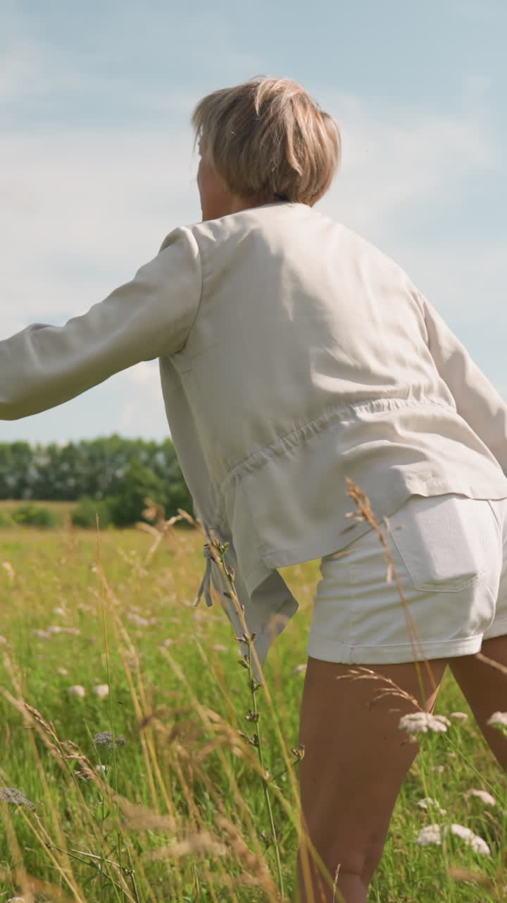 강아지 트레이너는 거리에 장난감을 던지고 그녀의 개는 은 하늘 아래 광활한 잔디에서 흥분하여 그것을 고 달려갑니다.트레이너는 왼손에 줄을 들고 놀이하는 야외 상호 작용을 보여줍니다.