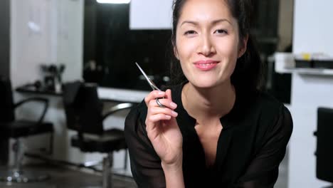 smiling female hairstylit holding scissor in salon