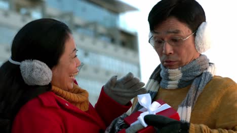 couple in warm clothing holding gift