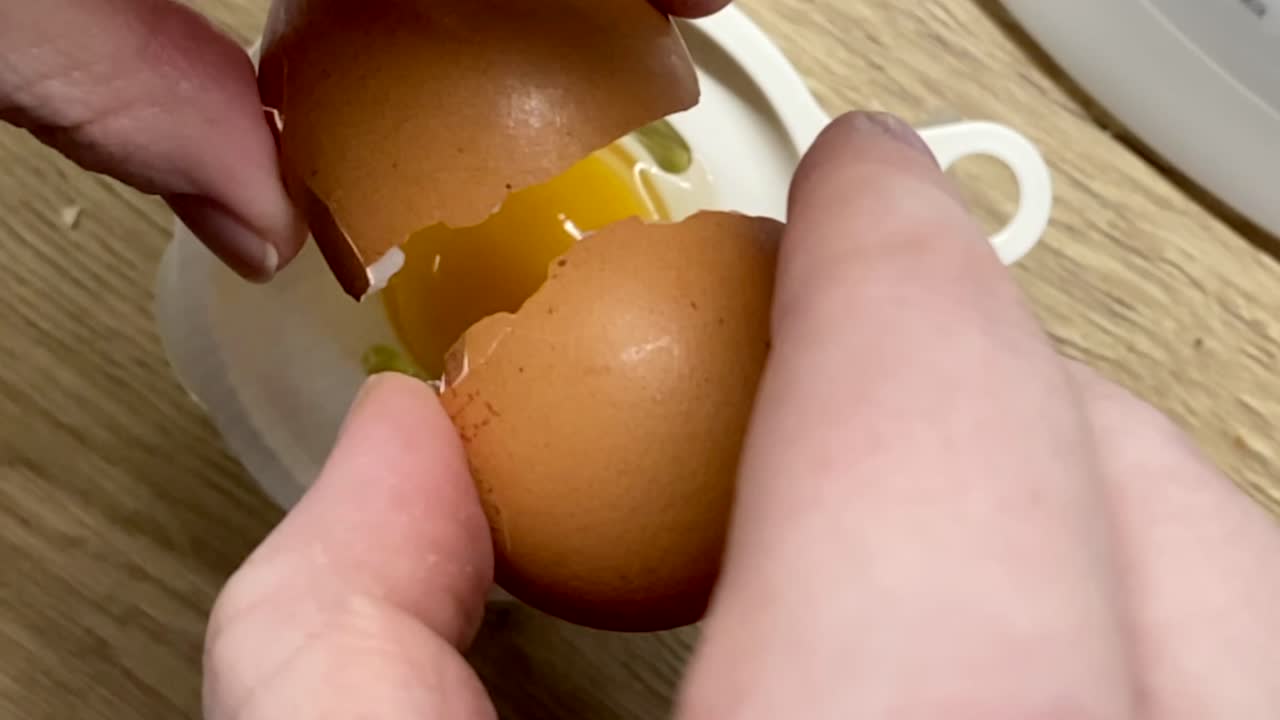 Hands Cracking Egg Into Egg Yolk Sifter In The Kitchen - overhead shot, slow motion