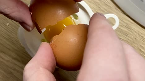 hands cracking egg into egg yolk sifter in the kitchen - overhead shot, slow motion