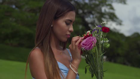 una niña huele el rostro de rosas y flores de cerca en un parque