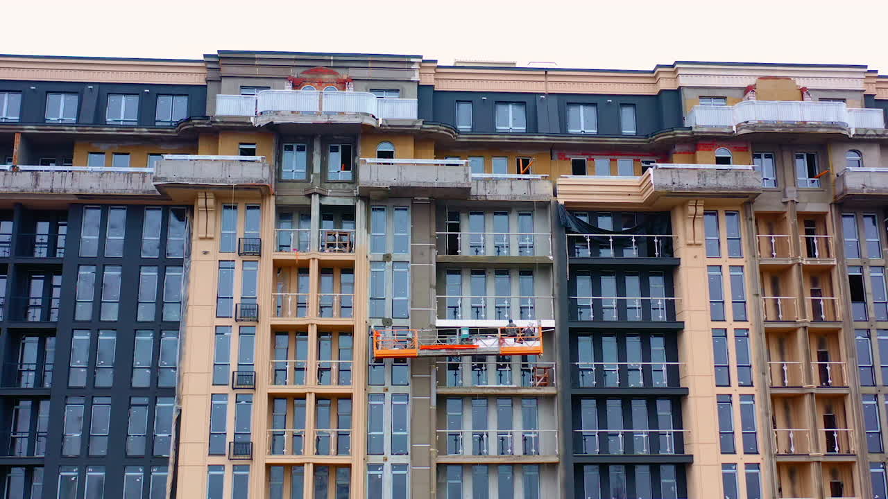 Building of a modern block of flats. Construction of a tower building in the city. Front view of a high-rise architecture.