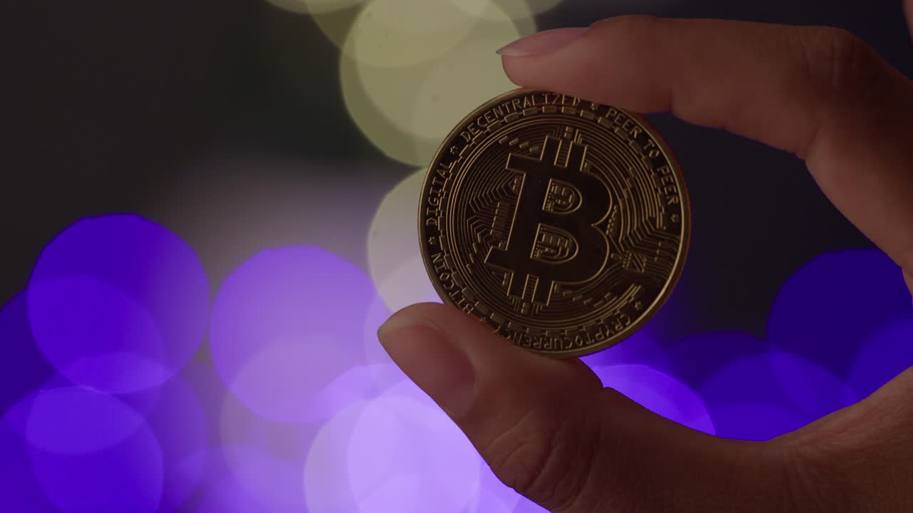 Ethereum, the smart contract crypto, held up by two fingers. 4K. Orange and blue bokeh balls in the background