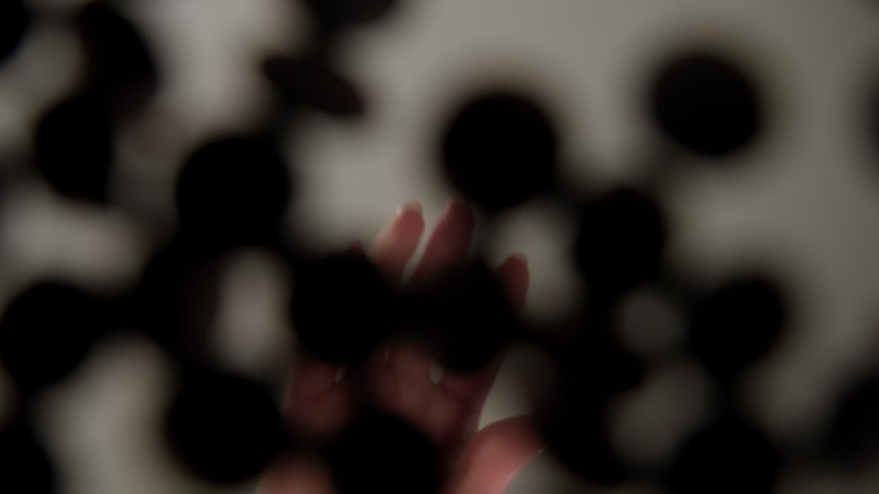 Primo piano di una mano che versa gocce di cioccolato durante la preparazione di dolci